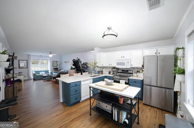 a kitchen with a refrigerator a stove and a dining table with wooden floor