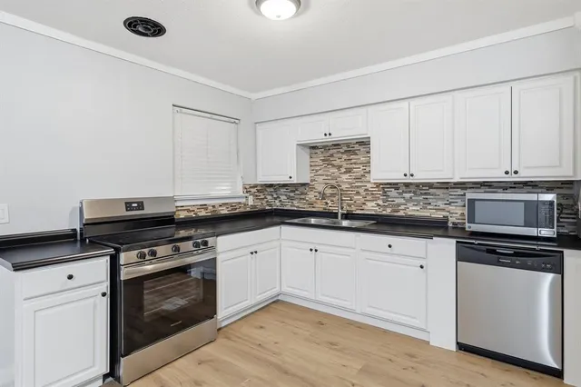 a kitchen with granite countertop a stove sink and cabinets