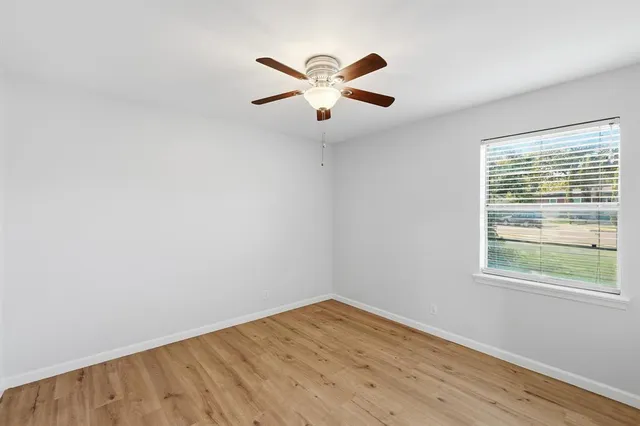 an empty room with window and ceiling fan