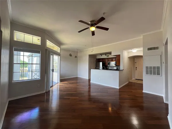 a view of an empty room with wooden floor and a ceiling fan