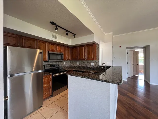 a kitchen with granite countertop a stove a sink and a refrigerator