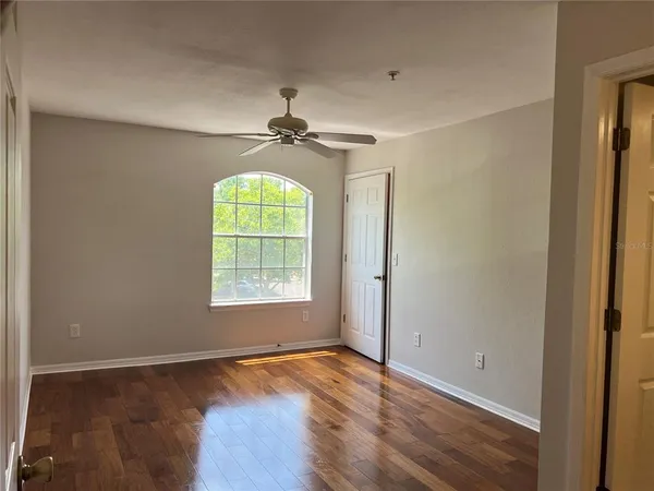 a view of a hallway with wooden floor and a bathroom