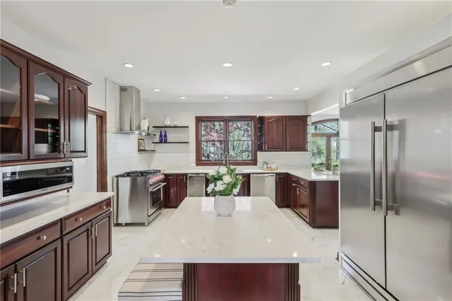 a kitchen with stainless steel appliances kitchen island granite countertop a refrigerator and a stove top oven