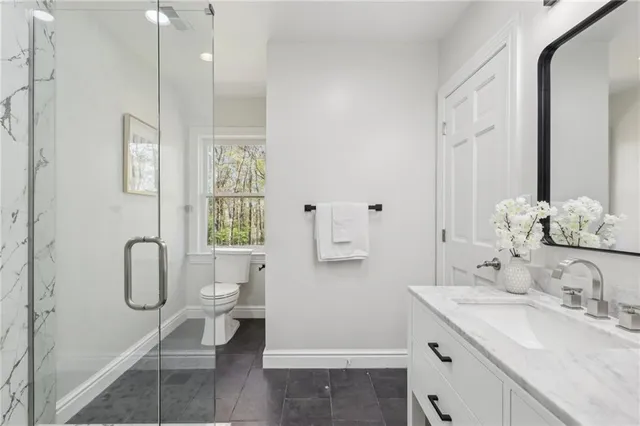 a bathroom with a granite countertop sink a toilet and shower