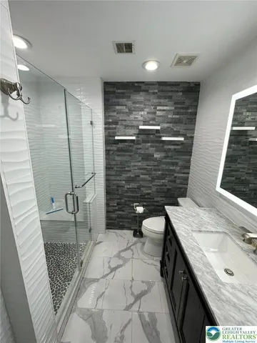 a bathroom with a granite countertop sink and mirror with shower