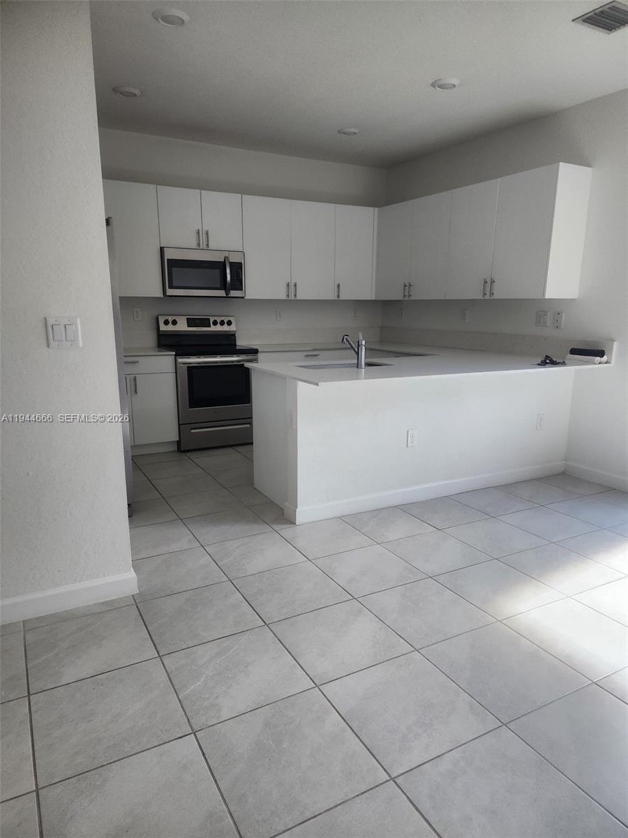 12946 Southwest 232nd Terrace, Unit 12946 Homestead, FL 33032 - Photo 3 of 11 a kitchen with cabinets and appliances