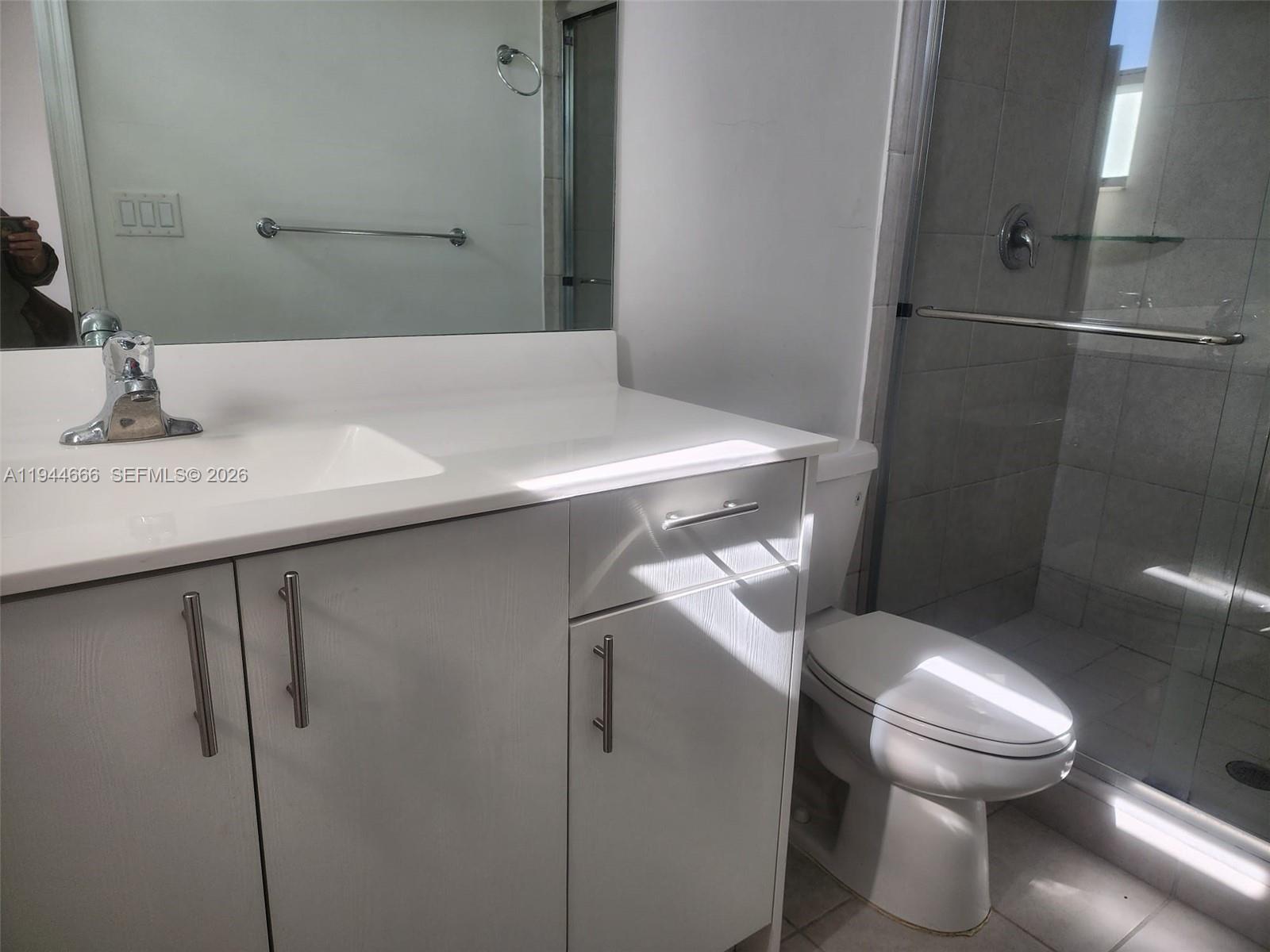 12946 Southwest 232nd Terrace, Unit 12946 Homestead, FL 33032 - Photo 7 of 11 a bathroom with a sink a toilet and shower