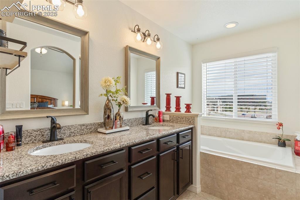 977 Salmon Pond Way Colorado Springs, CO 80921 - Photo 16 of 49 a bathroom with a granite countertop double vanity sink and a bathtub