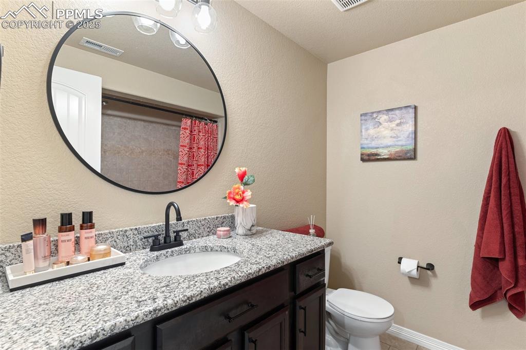 977 Salmon Pond Way Colorado Springs, CO 80921 - Photo 38 of 49 a bathroom with a granite countertop toilet a sink and a mirror
