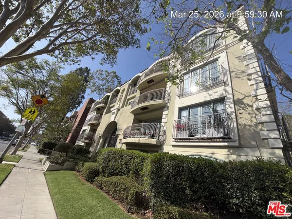 a front view of a multi story residential apartment building with yard and parking space
