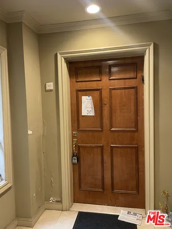 a view of hallway with stainless steel appliances a refrigerator and cabinet