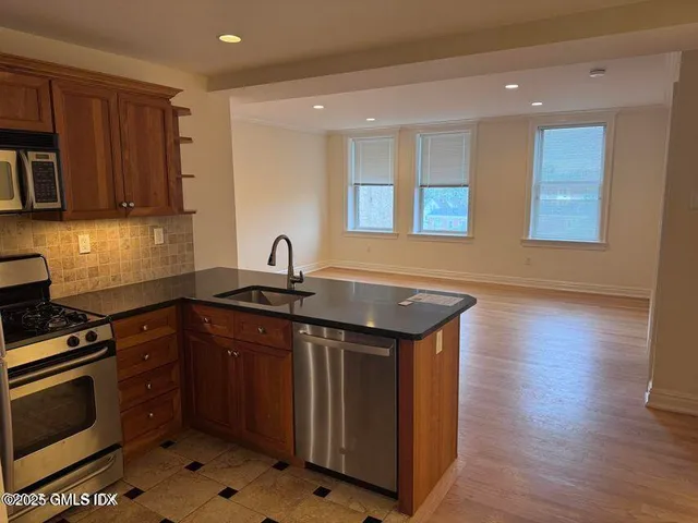 a kitchen with stainless steel appliances granite countertop a stove a sink and a microwave