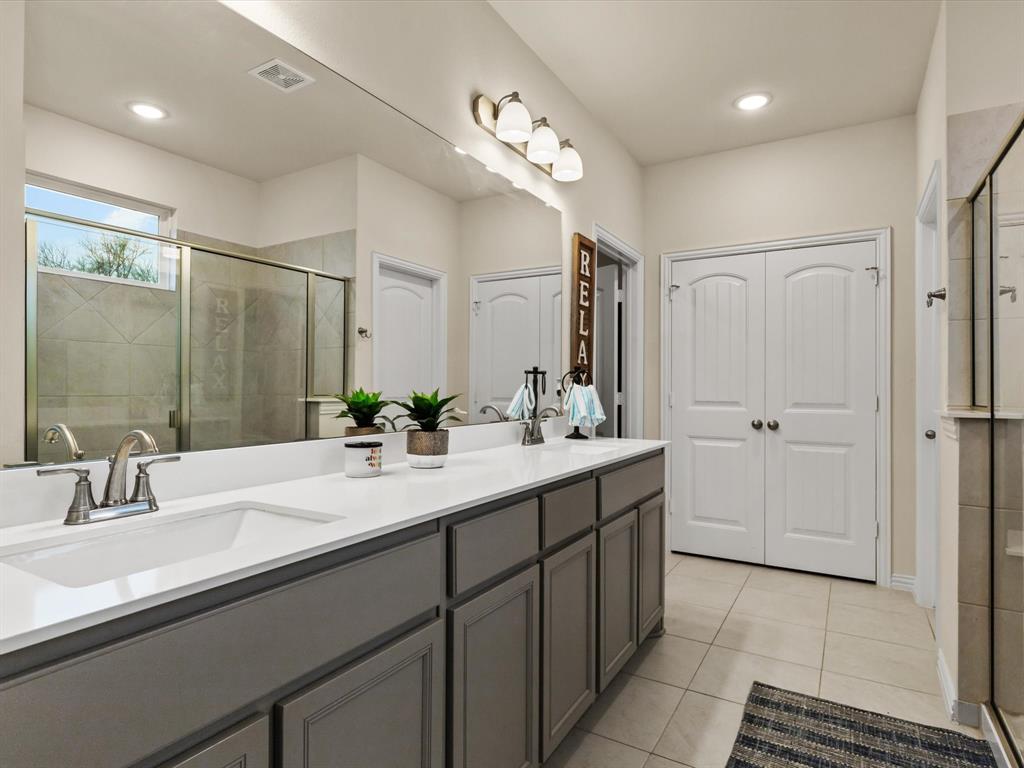 1009 Northern Oaks Court Springtown, TX 76082 - Photo 19 of 28 a bathroom with a double vanity sink a mirror and a shower