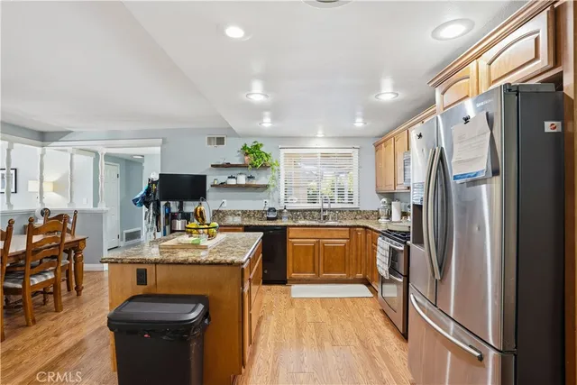 a kitchen with stainless steel appliances granite countertop a refrigerator a sink dishwasher a stove and white countertops with wooden floor