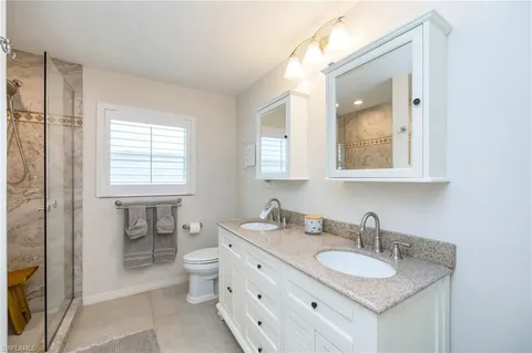 a bathroom with a granite countertop sink toilet and mirror