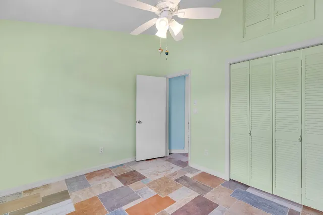 a view of an empty room with window and chandelier fan