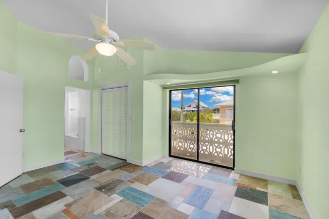 a view of an empty room with a window and a chandelier fan