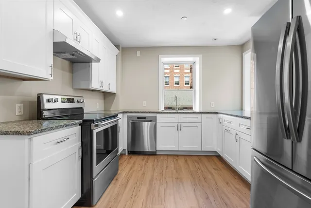 a kitchen with granite countertop stainless steel appliances a sink cabinets and a counter top space