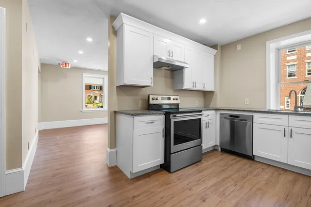 a kitchen with stainless steel appliances granite countertop a stove a sink and white cabinets