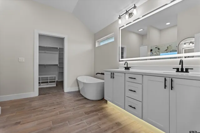 a spacious bathroom with a double vanity sink a mirror and a bathtub