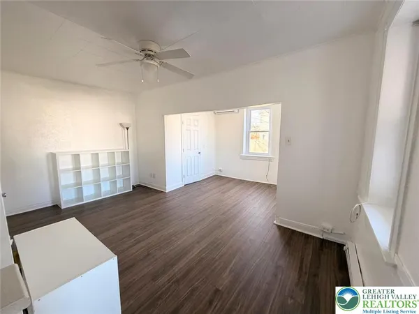 a view of an empty room with a window and wooden floor