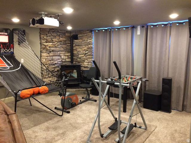 7030 West 2100 North Mendon, UT 84325 - Photo 63 of 67 Recreation space featuring a stone accent wall, ceiling-mounted projector, recessed lighting, and a wood-burning stove