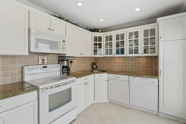 a kitchen with granite countertop white cabinets and white appliances