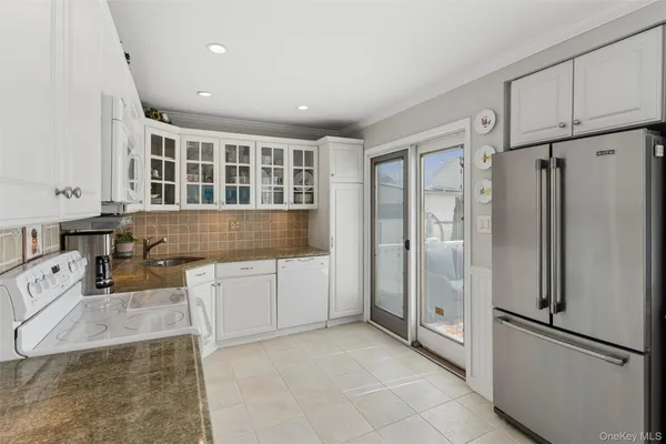 a kitchen with granite countertop a refrigerator and white cabinets