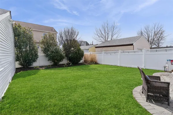 a view of a backyard with table and chairs potted plants and large tree