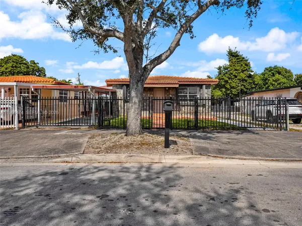 a view of a house with a tree and wooden fence