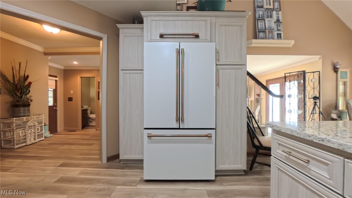7017 Kirk Road Canfield, OH 44406 - Photo 9 of 35 Kitchen featuring high end white fridge, ornamental molding, healthy amount of natural light, light wood-type flooring, and light stone countertops