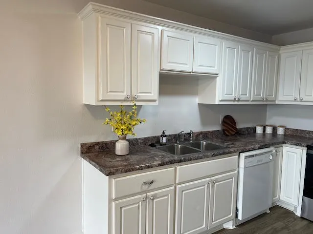a kitchen with granite countertop white cabinets white appliances and granite countertops with wooden floor