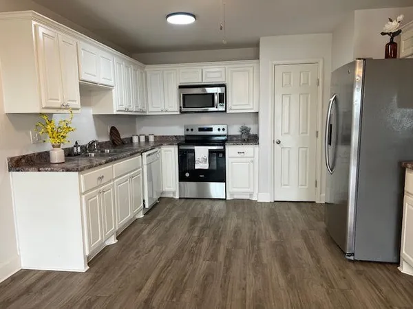 a kitchen with granite countertop a refrigerator stove top oven and sink