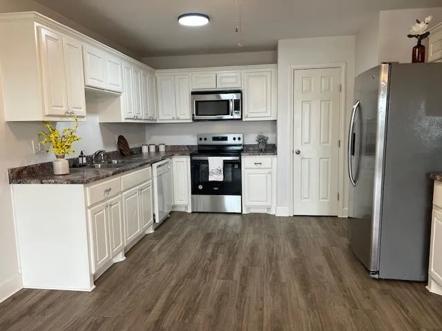 a kitchen with granite countertop a refrigerator stove top oven and sink