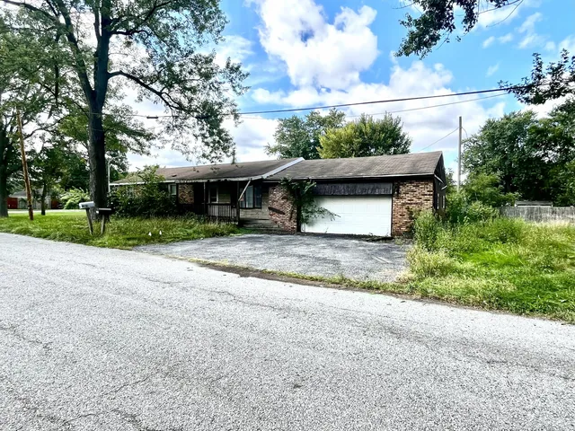 a view of a house with a yard and large tree