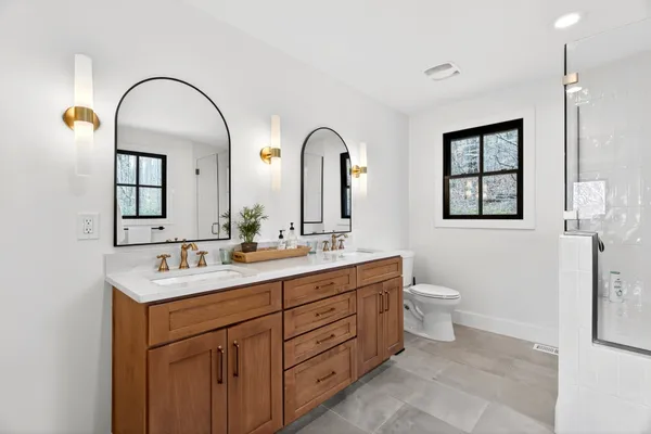 a bathroom with a double vanity sink toilet and a mirror