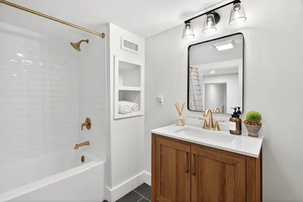 a bathroom with a granite countertop sink mirror and a bathtub