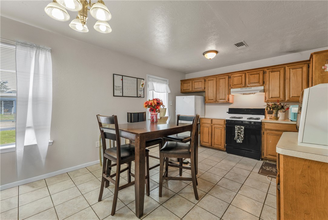 1011 West 17th Street Bryan, TX 77803 - Photo 2 of 6 a kitchen with stainless steel appliances granite countertop a stove a refrigerator a sink a dining table and chairs with wooden floor