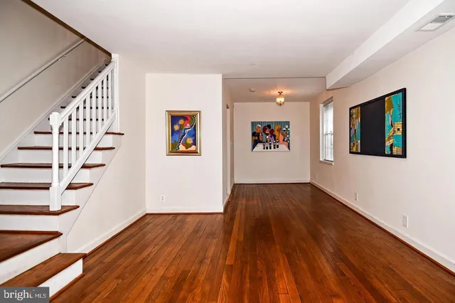 a view of an empty room with wooden floor and stairs