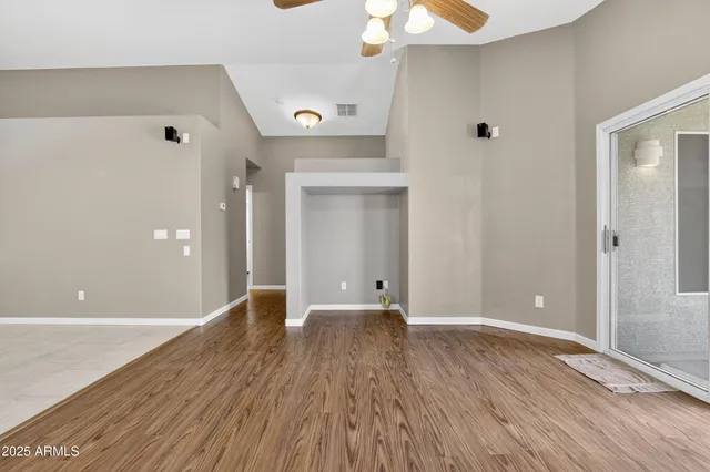 a view of an empty room with wooden floor and a window