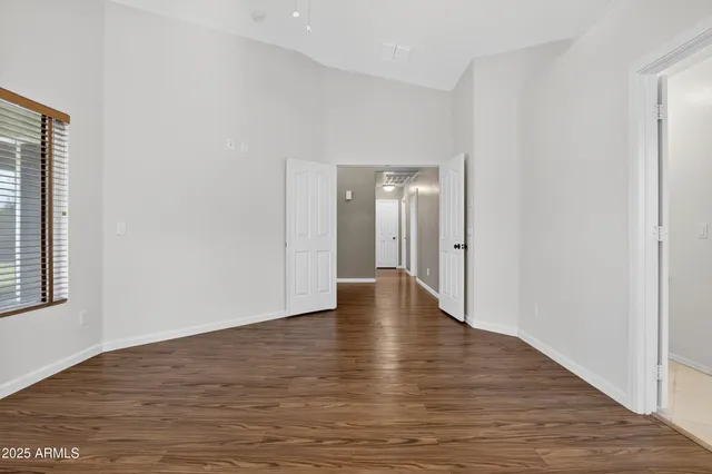 a view of an empty room with wooden floor and a ceiling fan