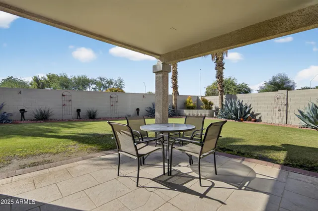 a view of a chairs and table in patio next to a yard