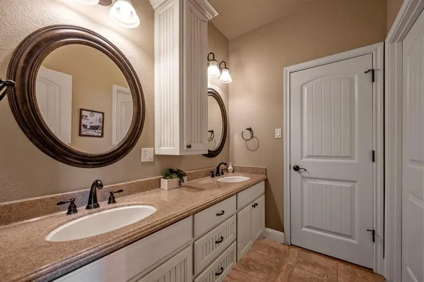a bathroom with a granite countertop double vanity sink and a mirror