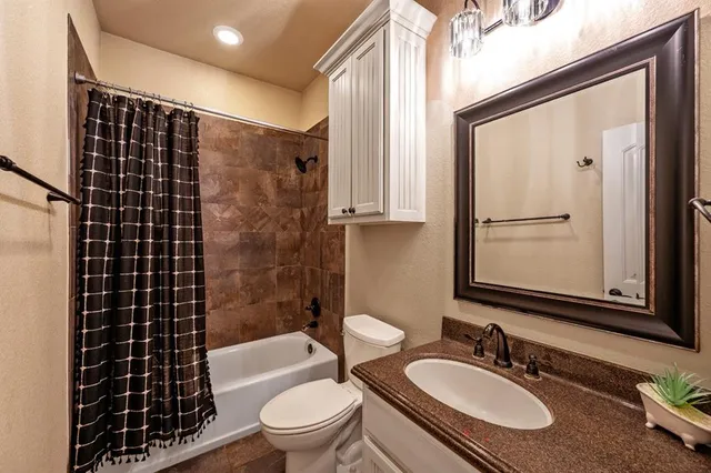 a bathroom with a granite countertop bathtub sink vanity mirror and toilet