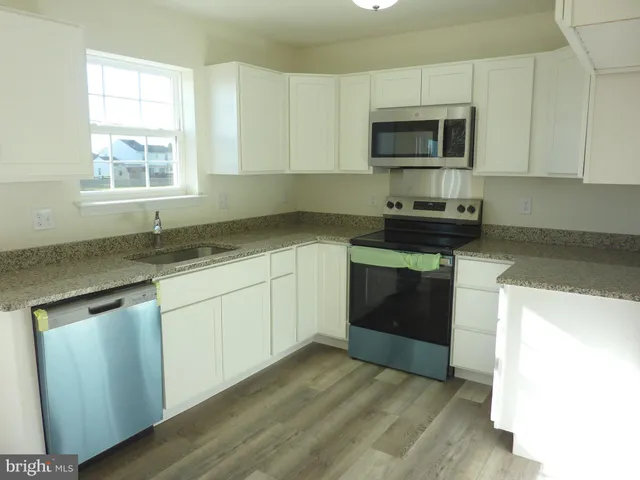 a kitchen with granite countertop a stove a sink and a microwave