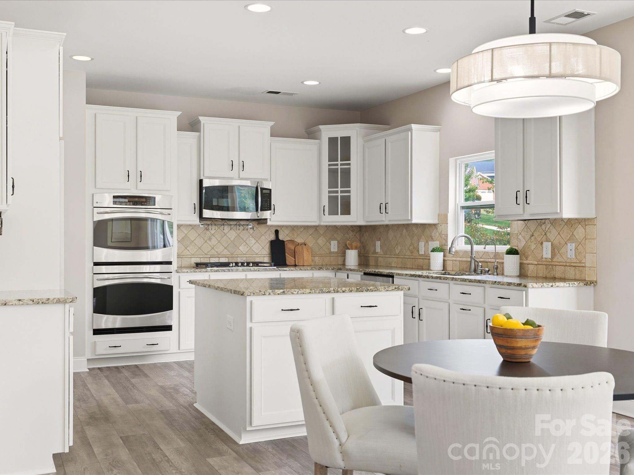 7196 Dove Field Lane Fort Mill, SC 29707 - Photo 10 of 35 a kitchen with stainless steel appliances granite countertop a sink a stove a microwave a refrigerator and white cabinets