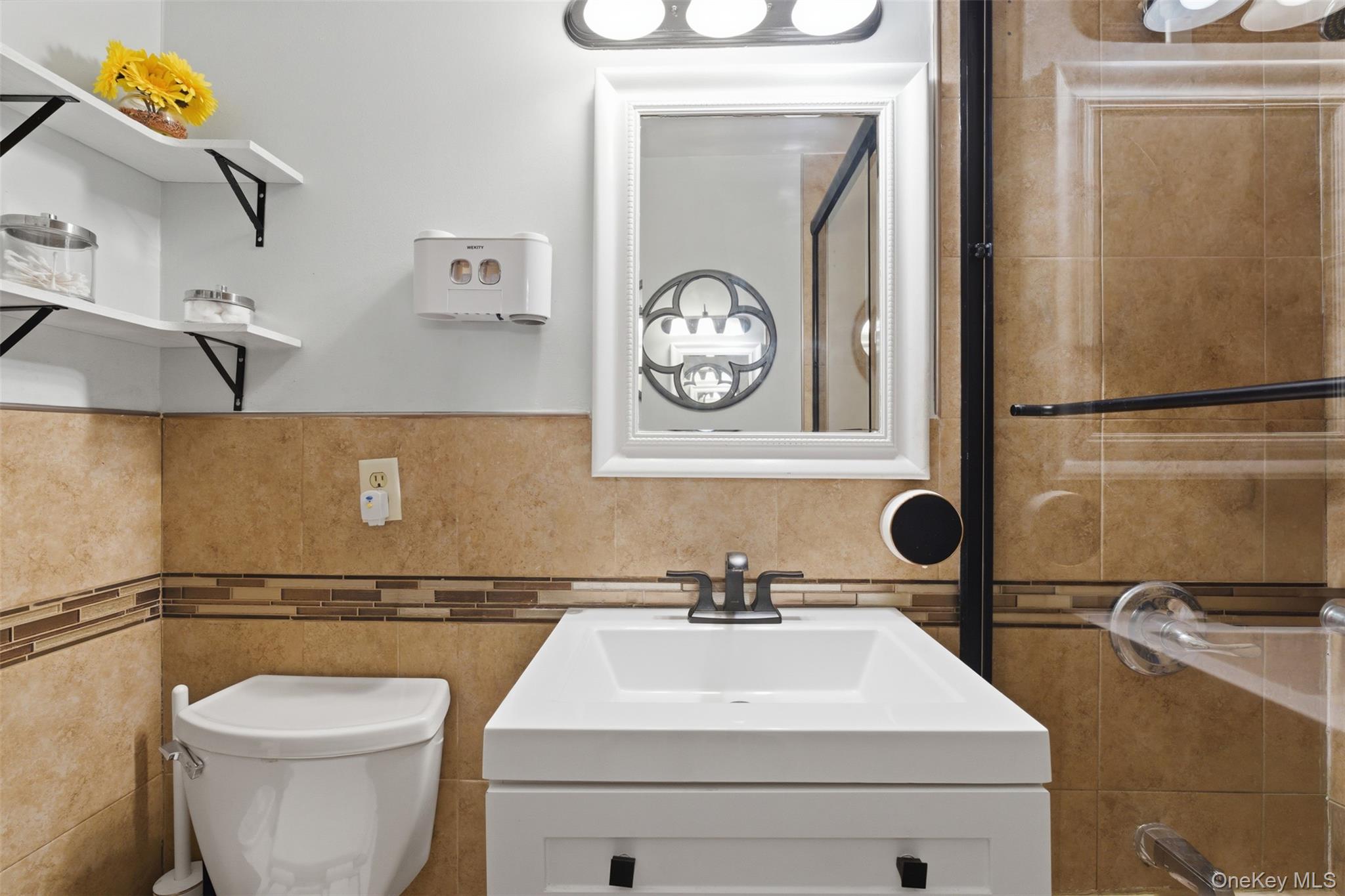 25 Trinity Place, Unit 2K New Rochelle, NY 10805 - Photo 14 of 24 This bathroom features a white vanity with a rectangular sink, a toilet, and a tiled shower with a new glass enclosure