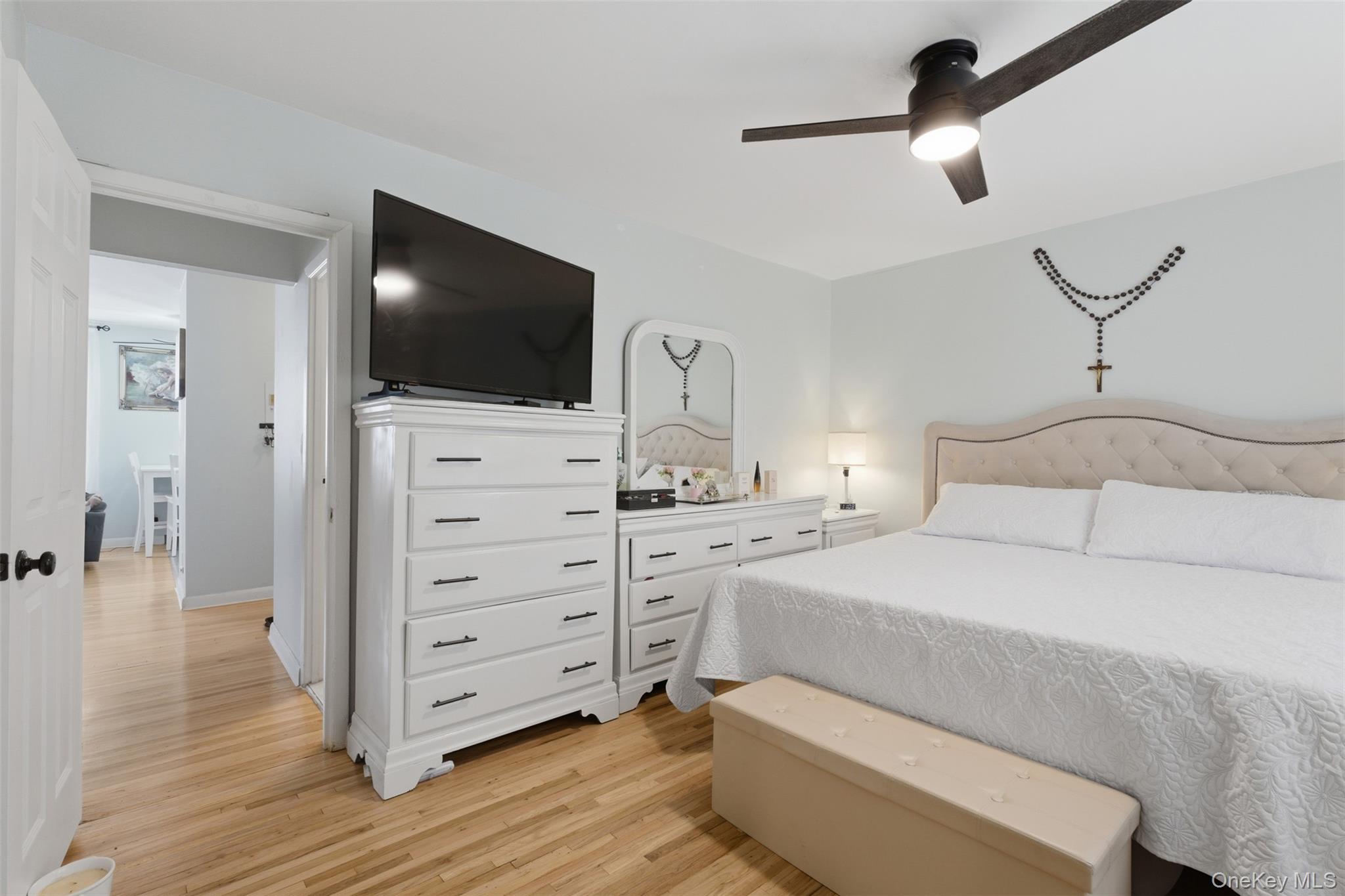 25 Trinity Place, Unit 2K New Rochelle, NY 10805 - Photo 16 of 24 Bedroom featuring light hardwood floors, a ceiling fan with integrated lighting, and a neutral-toned upholstered headboard