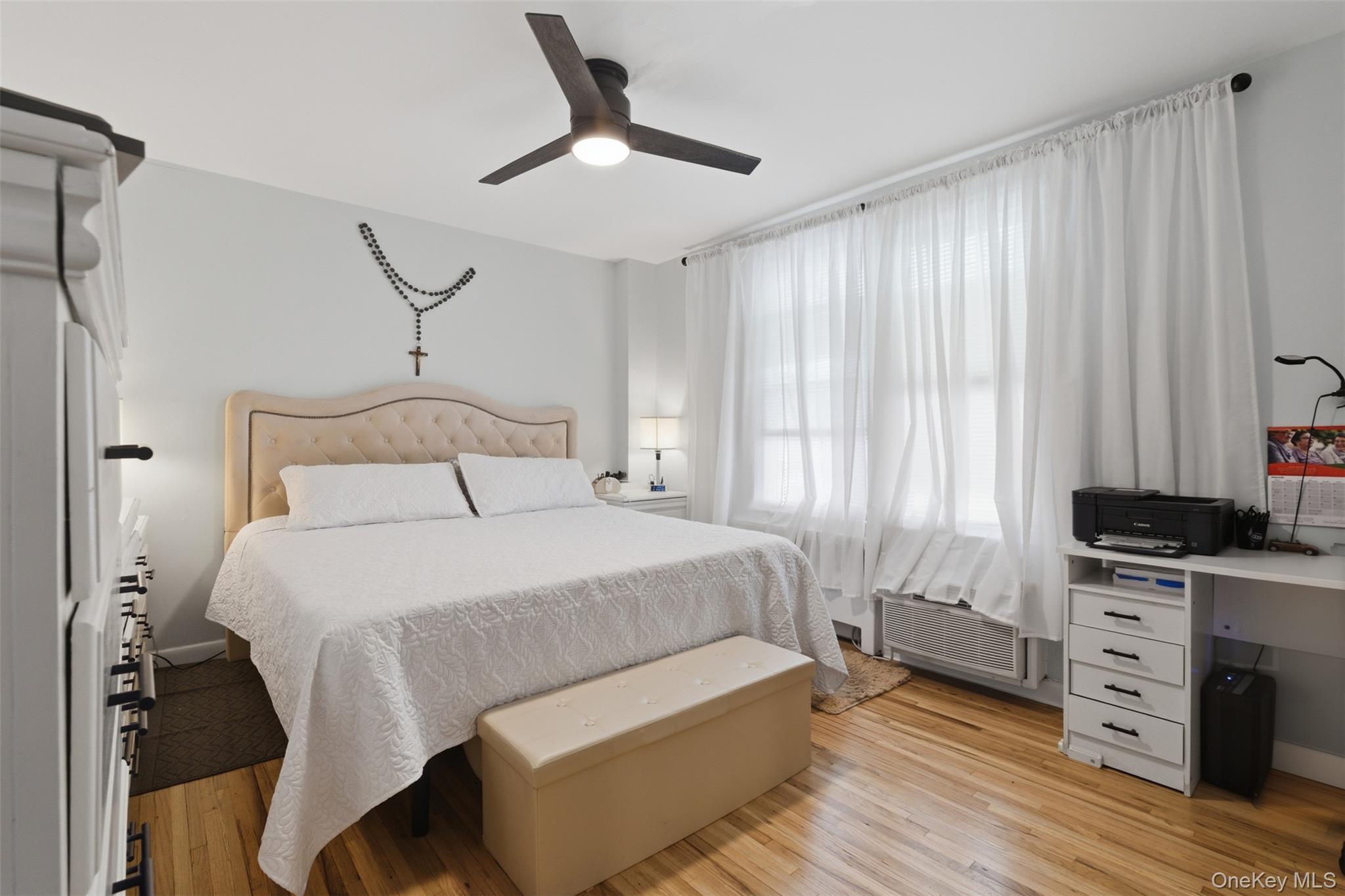 25 Trinity Place, Unit 2K New Rochelle, NY 10805 - Photo 18 of 24 This room features hardwood flooring, a ceiling fan with integrated lighting, and a large window providing ample natural light