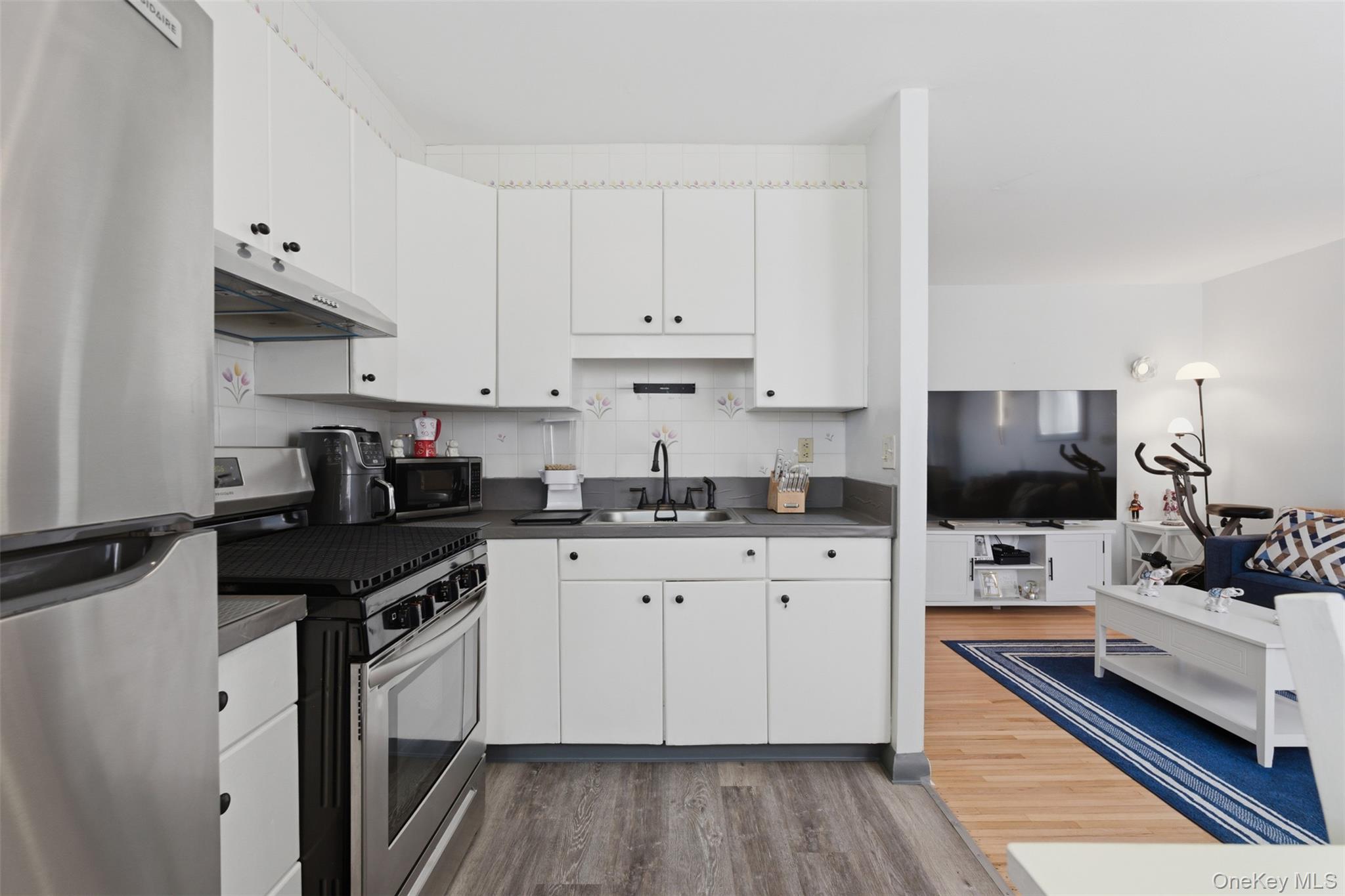 25 Trinity Place, Unit 2K New Rochelle, NY 10805 - Photo 6 of 24 The kitchen features white cabinetry, a stainless steel refrigerator, and a gas range